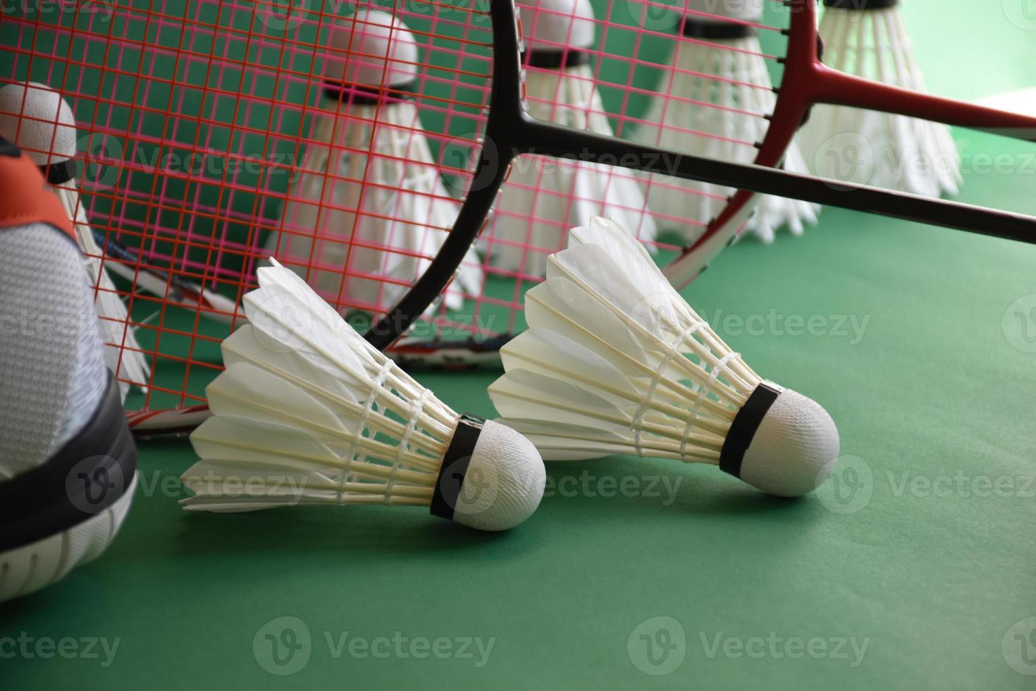 équipements de sport de badminton sur le sol vert du terrain de badminton volants, raquettes, chaussures, mise au point sélective sur les volants, sport de badminton jouant aux amoureux du concept mondial. photo