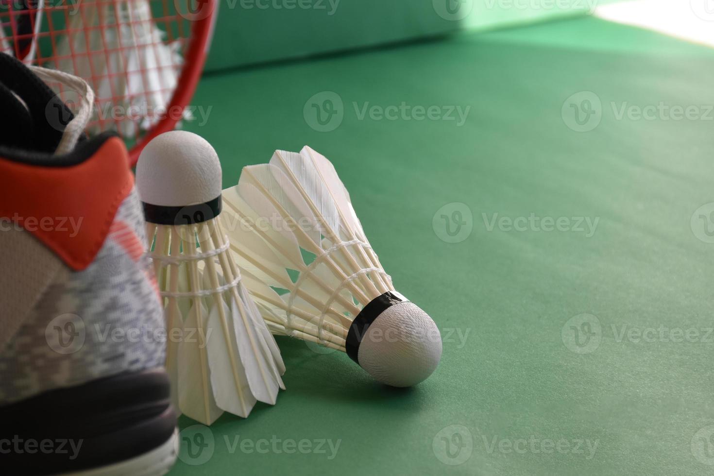 équipements de sport de badminton sur le sol vert du terrain de badminton volants, raquettes, chaussures, mise au point sélective sur les volants, sport de badminton jouant aux amoureux du concept mondial. photo