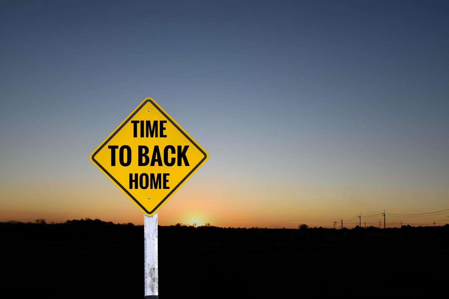 panneau de signalisation à étiquette jaune sur le poteau qui a des textes « temps de retour à la maison » avec arrière-plan flou au coucher du soleil, concept pour informer le conducteur de conduire le véhicule directement à la maison pour rester avec sa famille dans le monde entier. photo