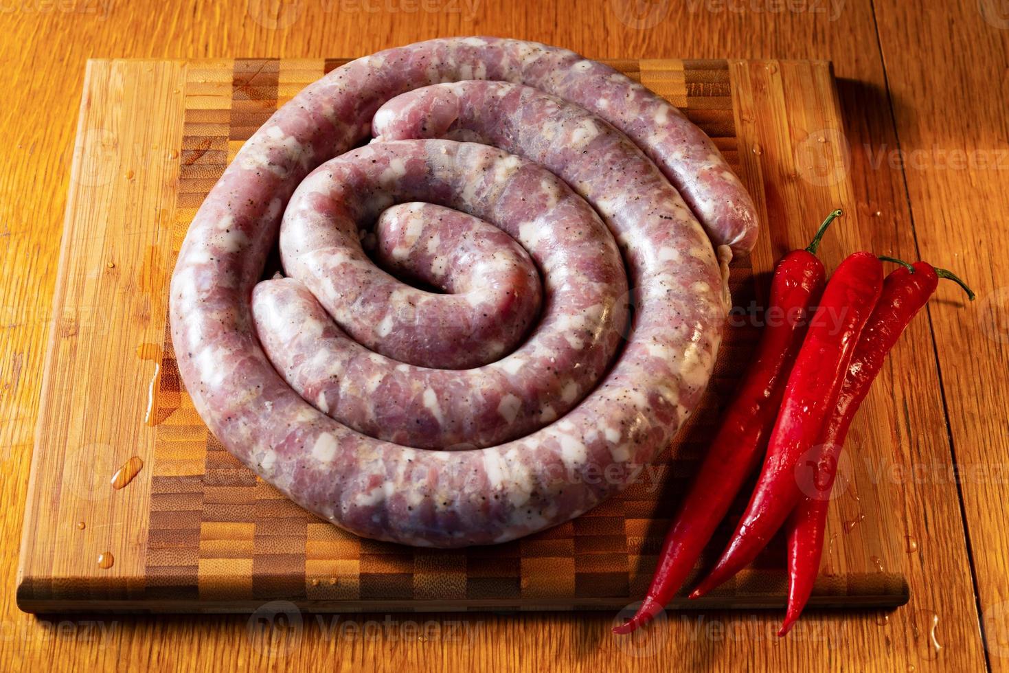 saucisses crues sur une planche à découper avec du poivron rouge photo