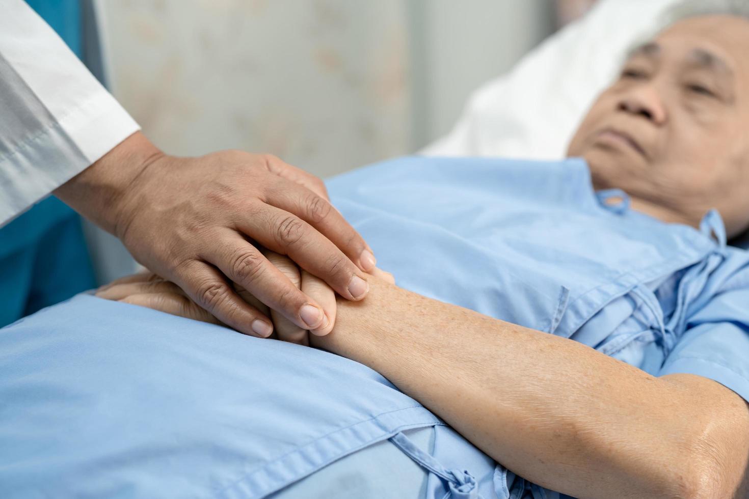 médecin tenant des mains touchantes femme âgée ou vieille dame asiatique patiente avec amour, soins, aide, encouragement et empathie à l'hôpital de soins infirmiers, concept médical fort et sain photo