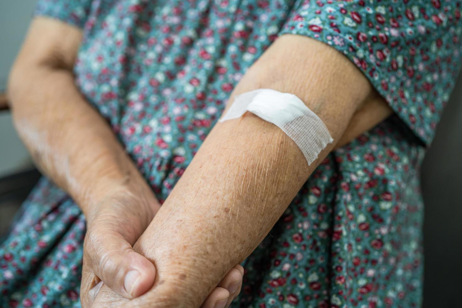 Une patiente asiatique âgée ou âgée montre que le coton arrête de saigner, après des tests sanguins pour un bilan de santé physique annuel afin de vérifier le cholestérol, la pression artérielle et le taux de sucre. photo