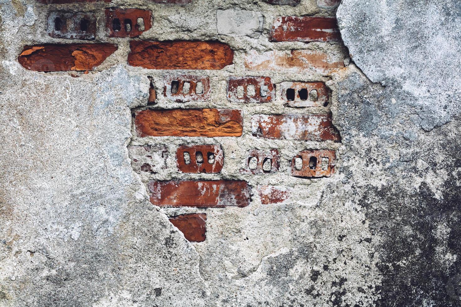 vieux mur endommagé avec des briques rouges visibles à travers. photo