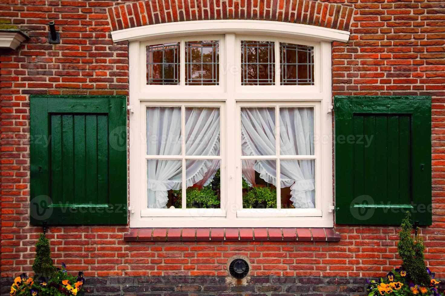 Vieille fenêtre rétro avec volets sur maison en brique rouge photo