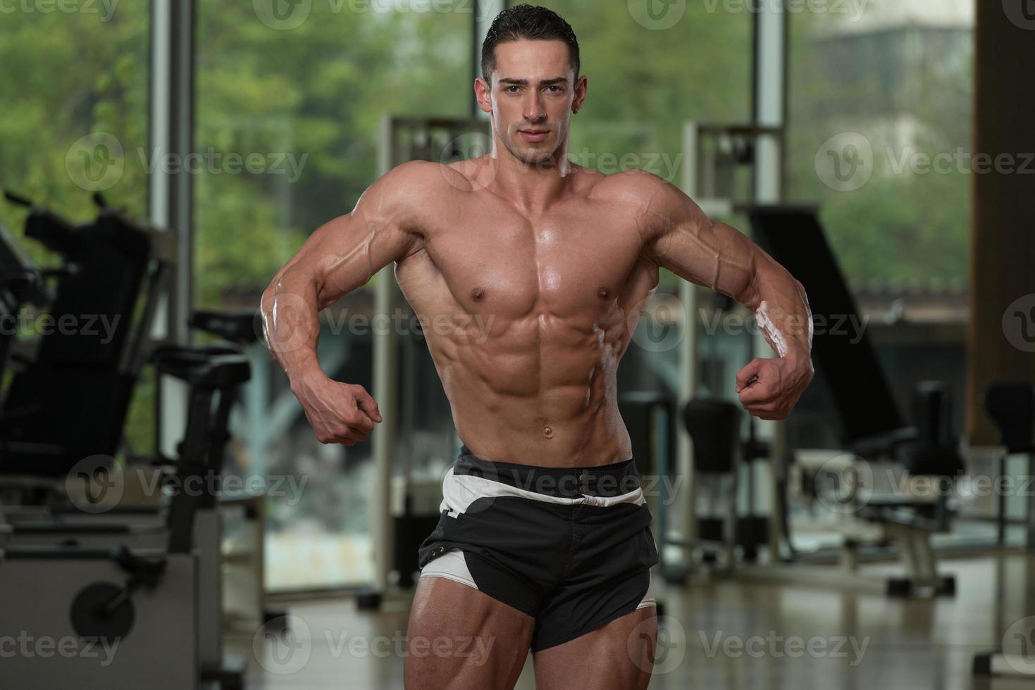 bodybuilder sérieux debout dans la salle de gym photo