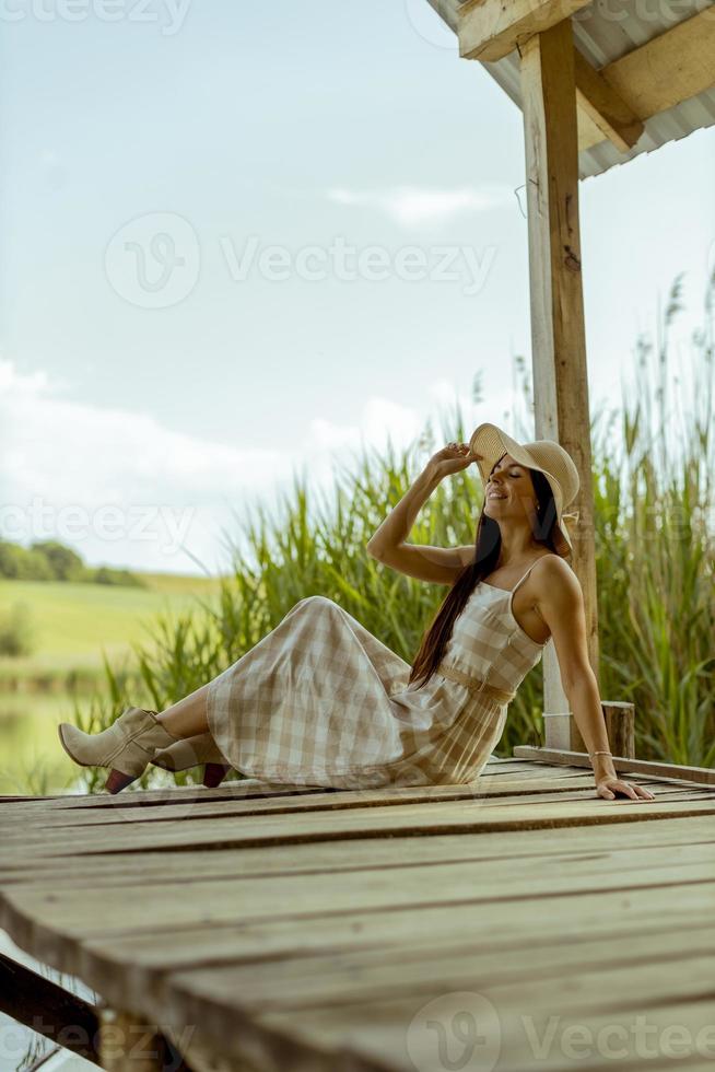 jeune femme se reposant sur la jetée en bois au bord du lac calme photo