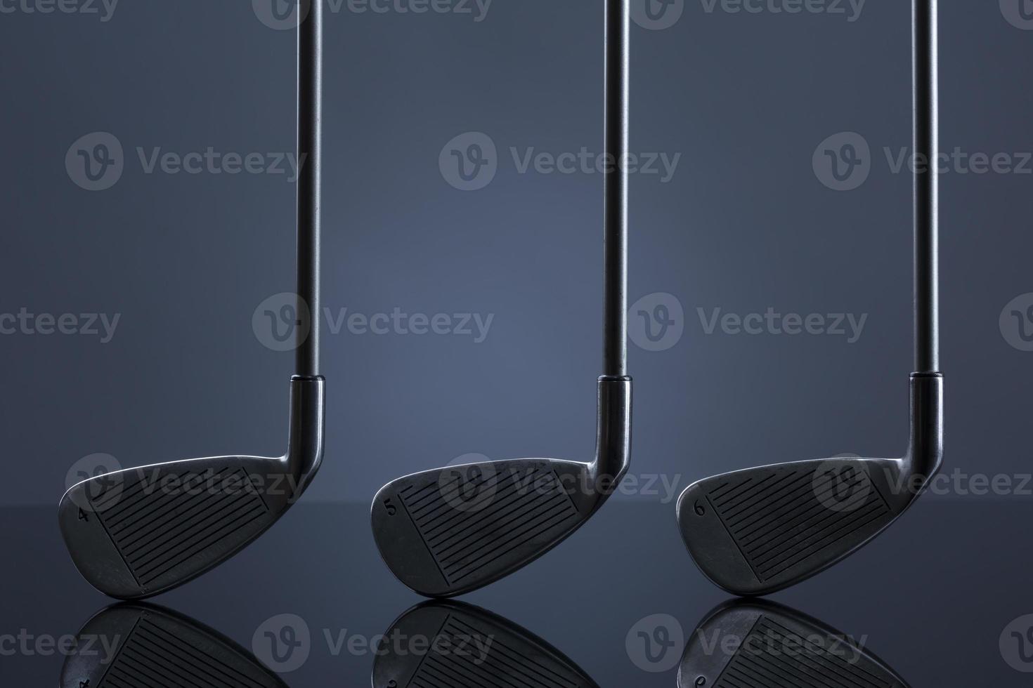 clubs de golf debout sur une surface réfléchissante, isolé sur fond sombre. photo