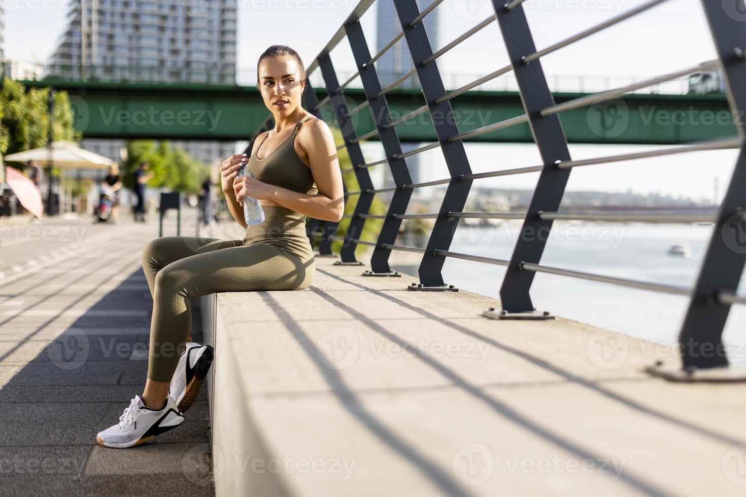 jeune femme prenant une pause pendant l'exercice sur la promenade de la rivière photo