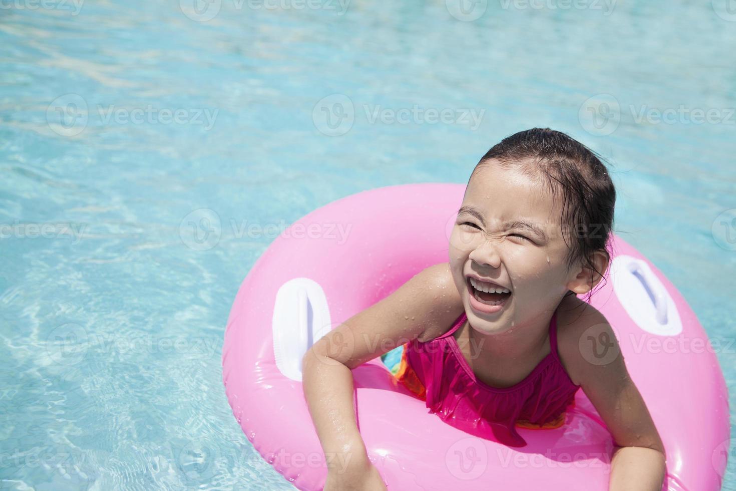 mignonne petite fille nageant dans la piscine avec un tube rose photo