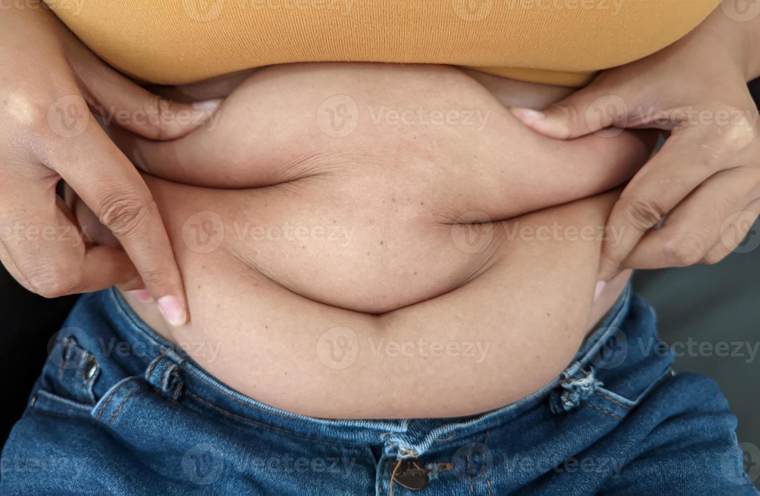 femmes asiatiques assises sur le ventre de graisse corporelle show de heureux de manger. photo