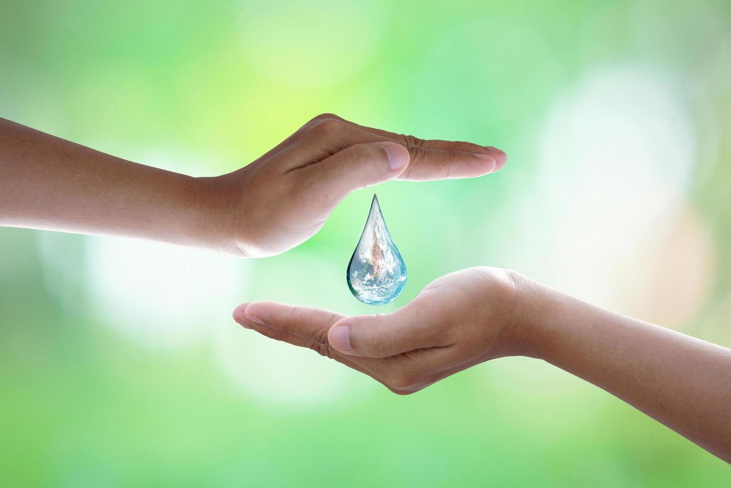 journée mondiale de l'environnement. main humaine protégeant la goutte d'eau avec la lumière du soleil sur fond de nature verdoyante. photo