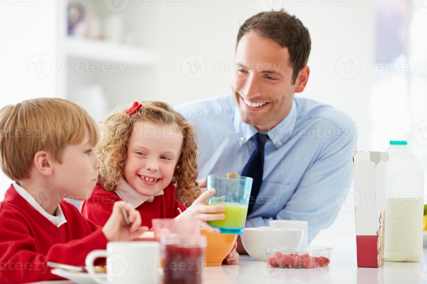 père et enfants prenant le petit déjeuner dans la cuisine ensemble photo