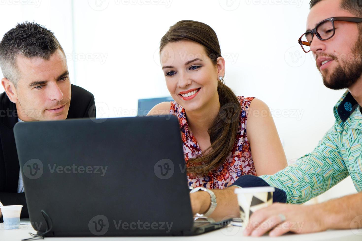 cadres occasionnels travaillant ensemble lors d'une réunion avec un ordinateur portable. photo