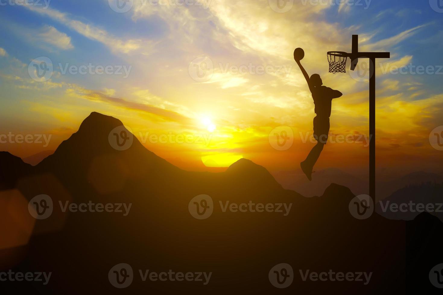 conduite et objectifs un homme place un but de basket-ball au sommet d'une montagne avec le coucher du soleil photo