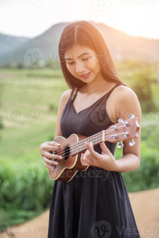 belle femme tenant une guitare sur son épaule, parc naturel été à l'extérieur. photo