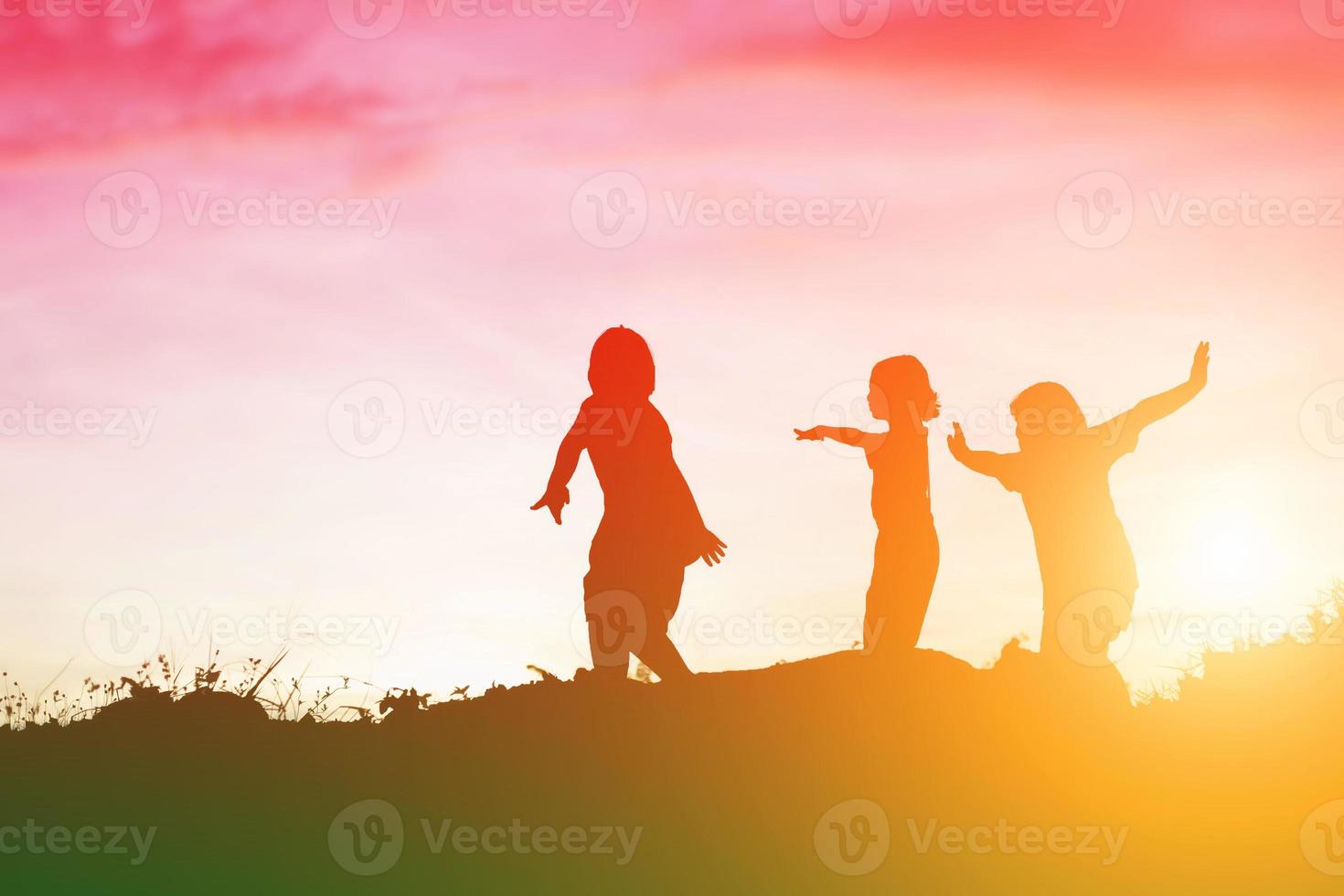 silhouette d'enfants heureux et coucher de soleil heureux photo
