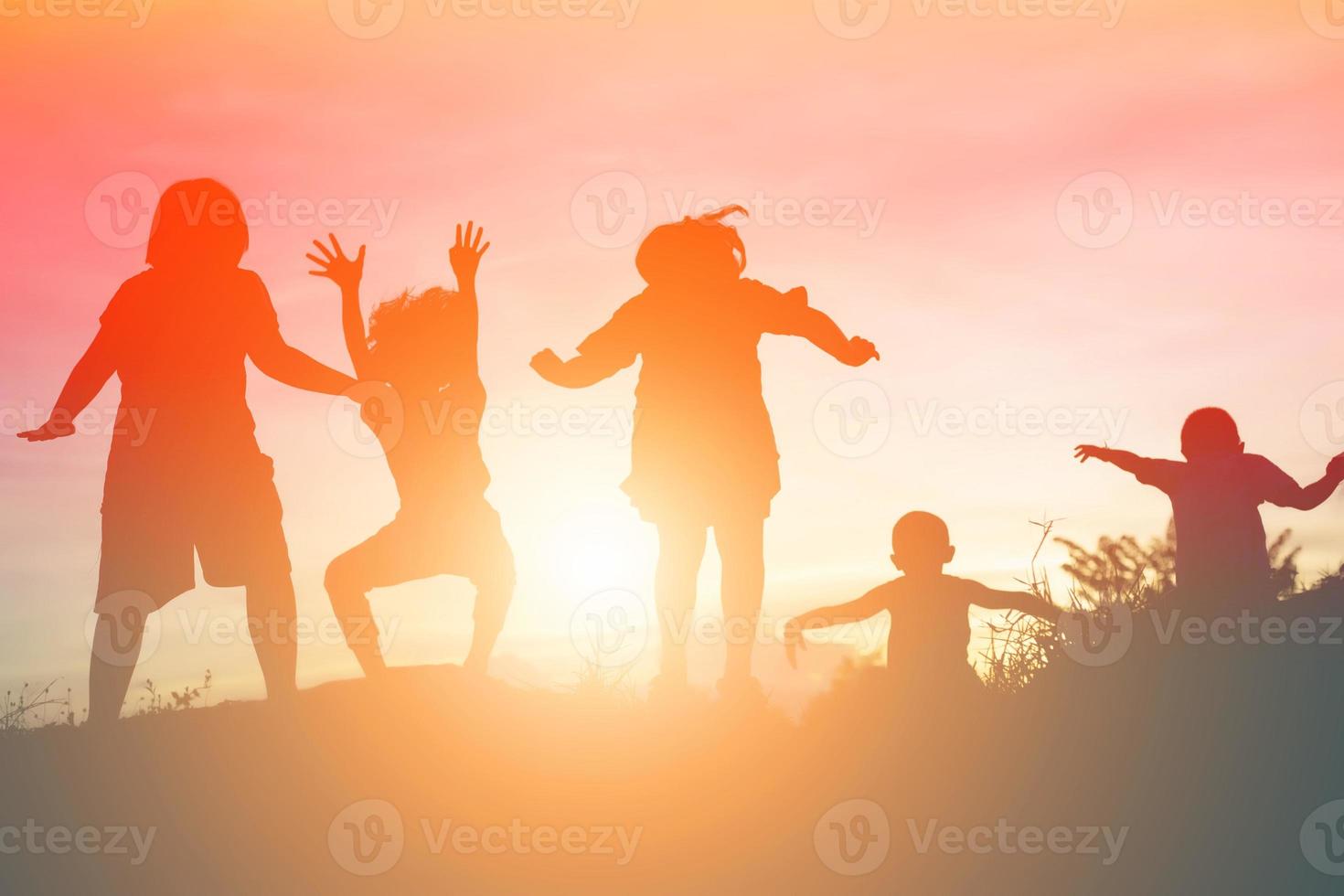 silhouette d'enfants heureux et coucher de soleil heureux photo