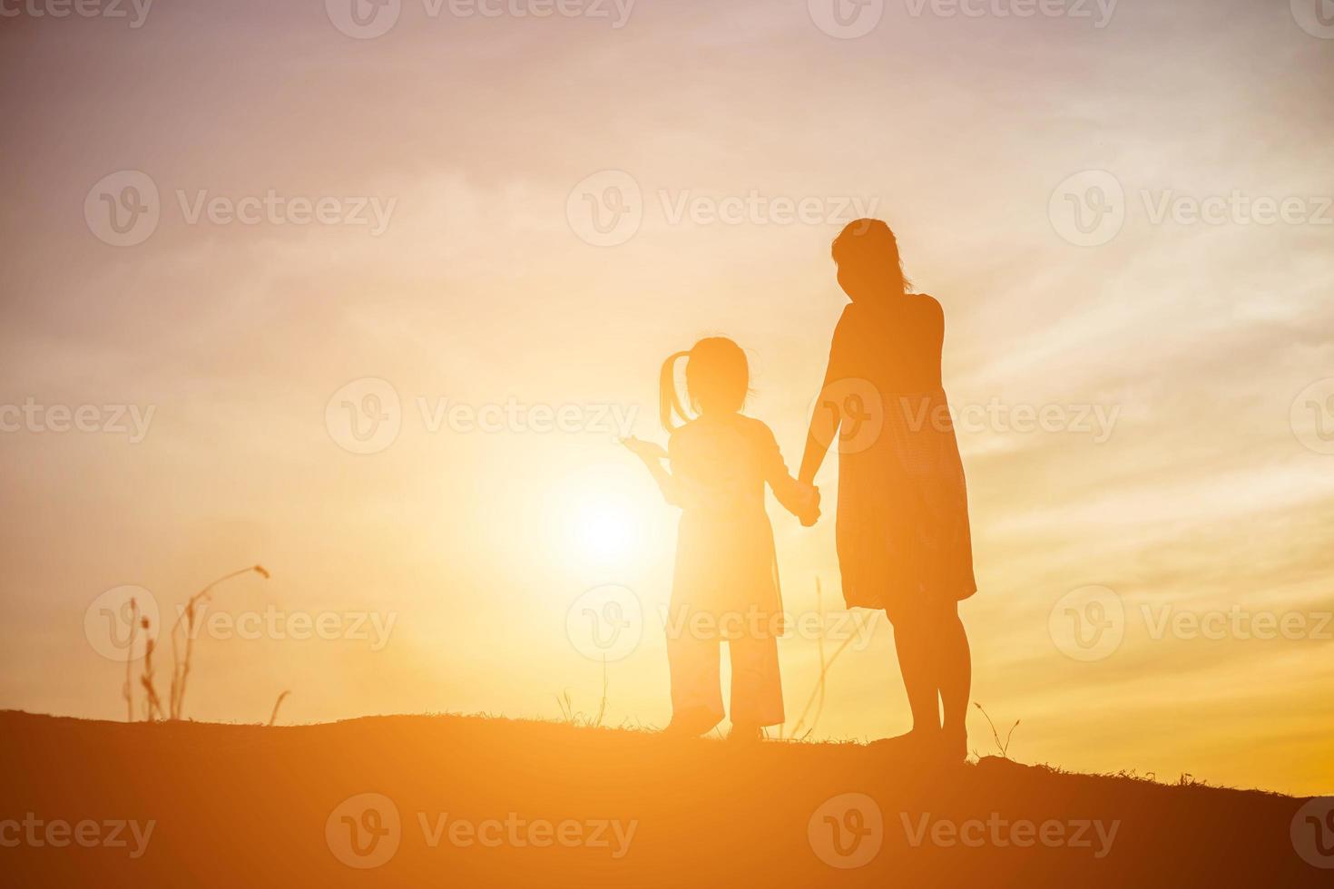 mère a encouragé sa fille à sortir de l'ombre au coucher du soleil. photo