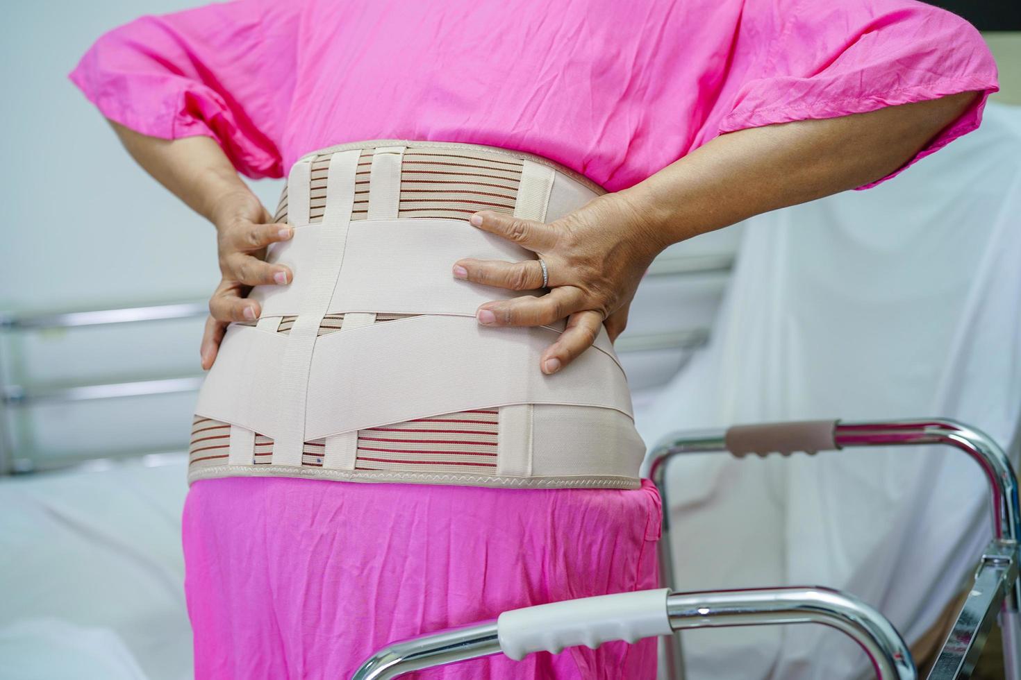 dos de douleur senior asiatique portant une ceinture de soutien élastique avec déambulateur. photo