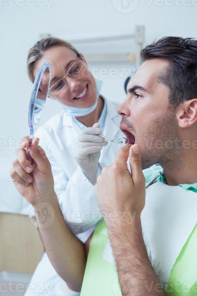 homme regardant miroir par femme dentiste photo