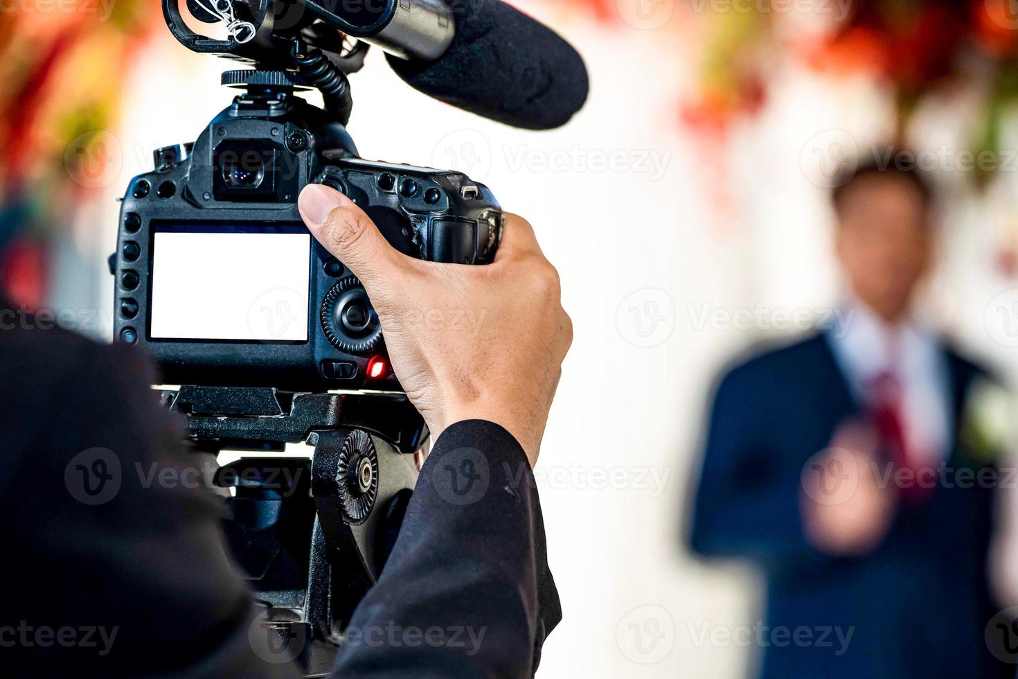 une vidéaste à l'arrière filme et enregistre une vidéo lors d'un événement de mariage. photo