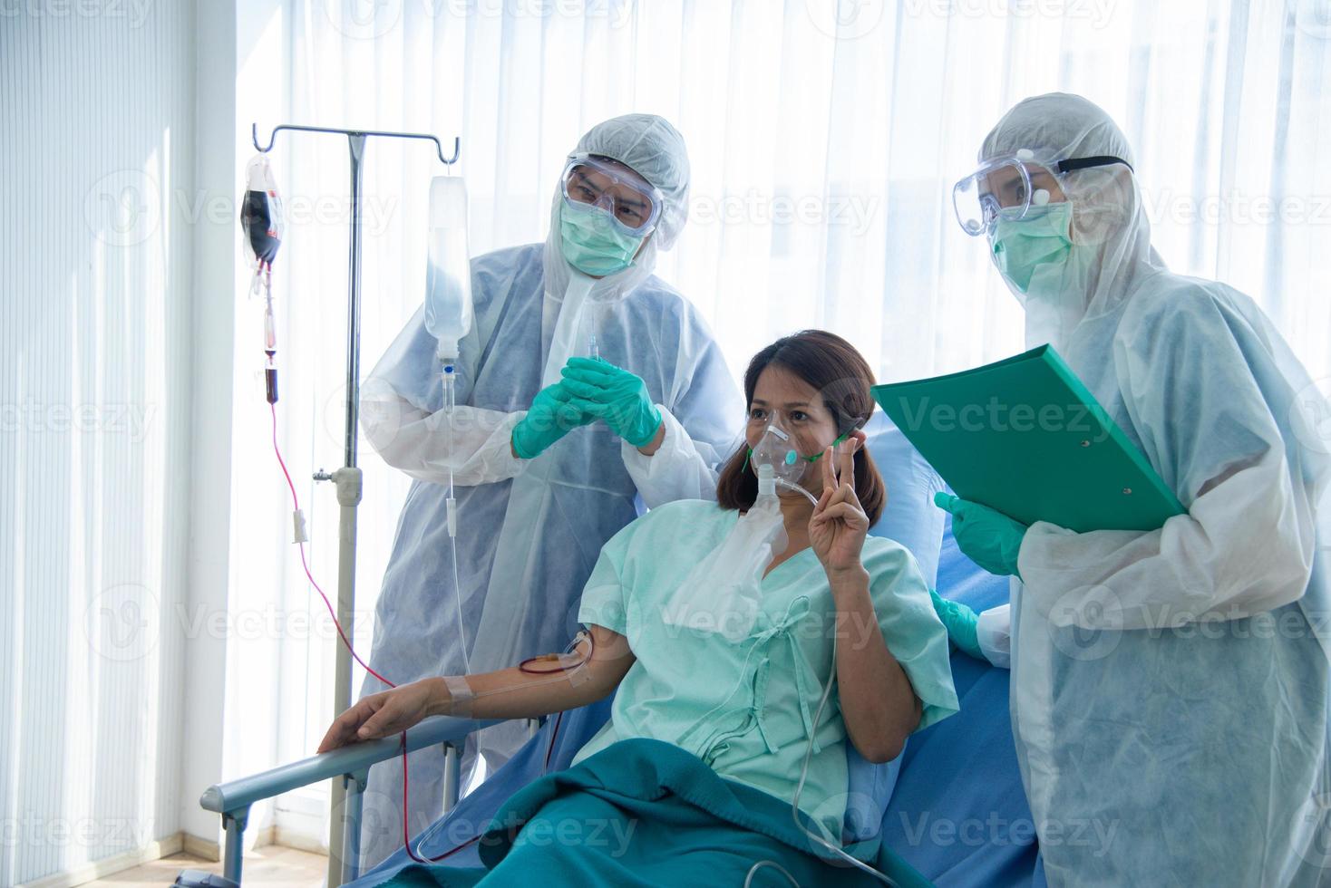 les médecins en tenue de protection surveillent et vérifient le patient infecté par le corona visrus ou la température covid-19 dans la salle de quarantaine de l'hôpital. les médecins prennent une photo avec le patient.