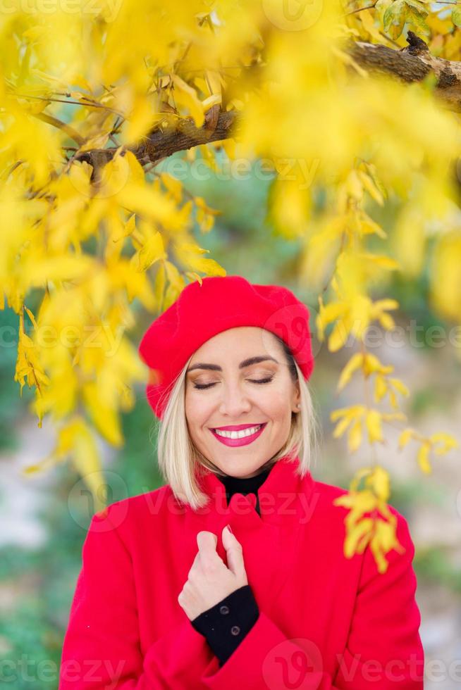 dame élégante ravie souriante et appréciant la nature d'automne avec les yeux fermés photo