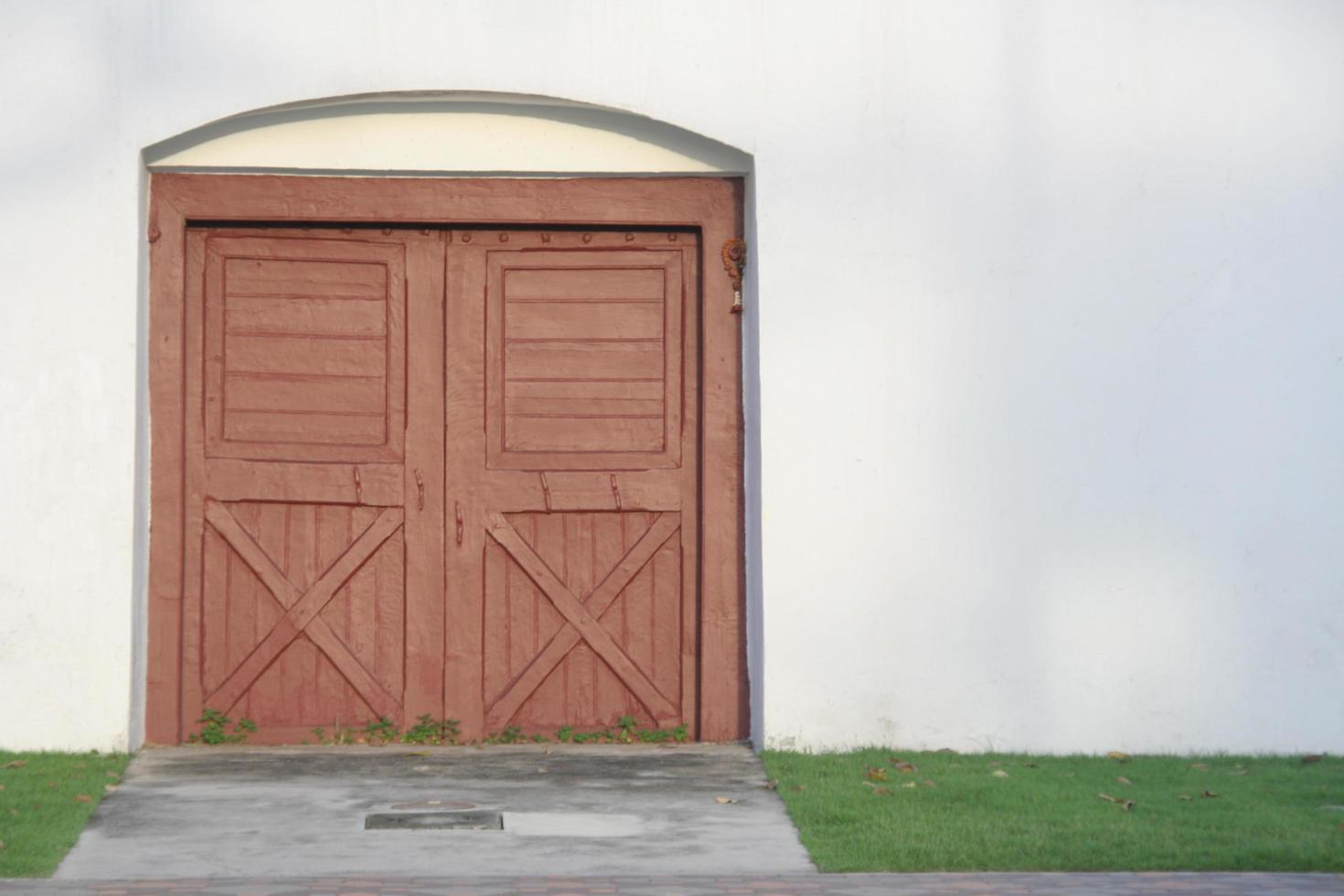 porte en bois peint brun rouge et mur blanc, thaïlande. une petite cour devant la porte. photo