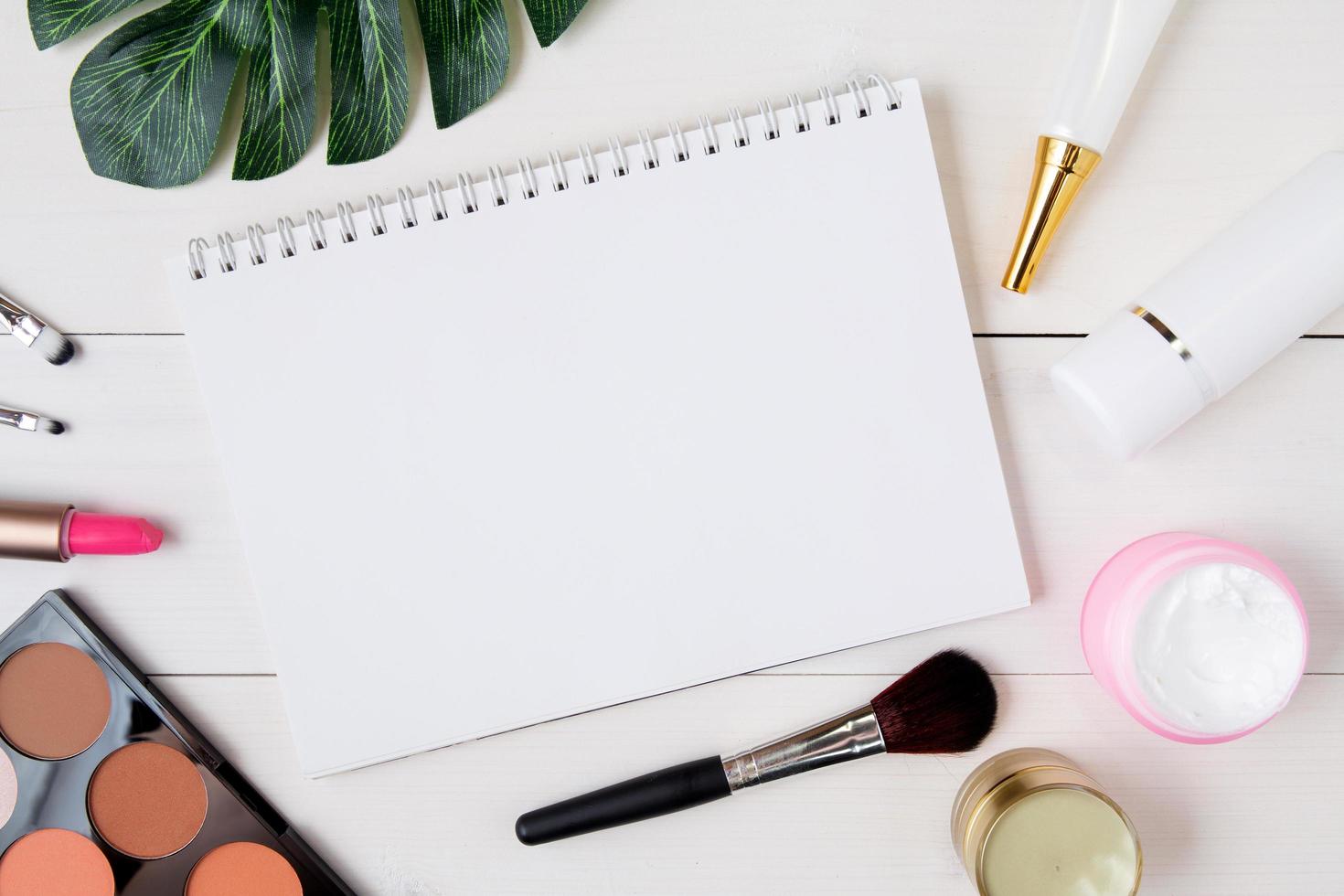 produit cosmétique et de soin de la peau et cahier sur une table en bois blanc, beauté avec crème de traitement et espace de copie hydratant et bloc-notes sur un bureau en bois, concept de santé et de bien-être, vue de dessus. photo