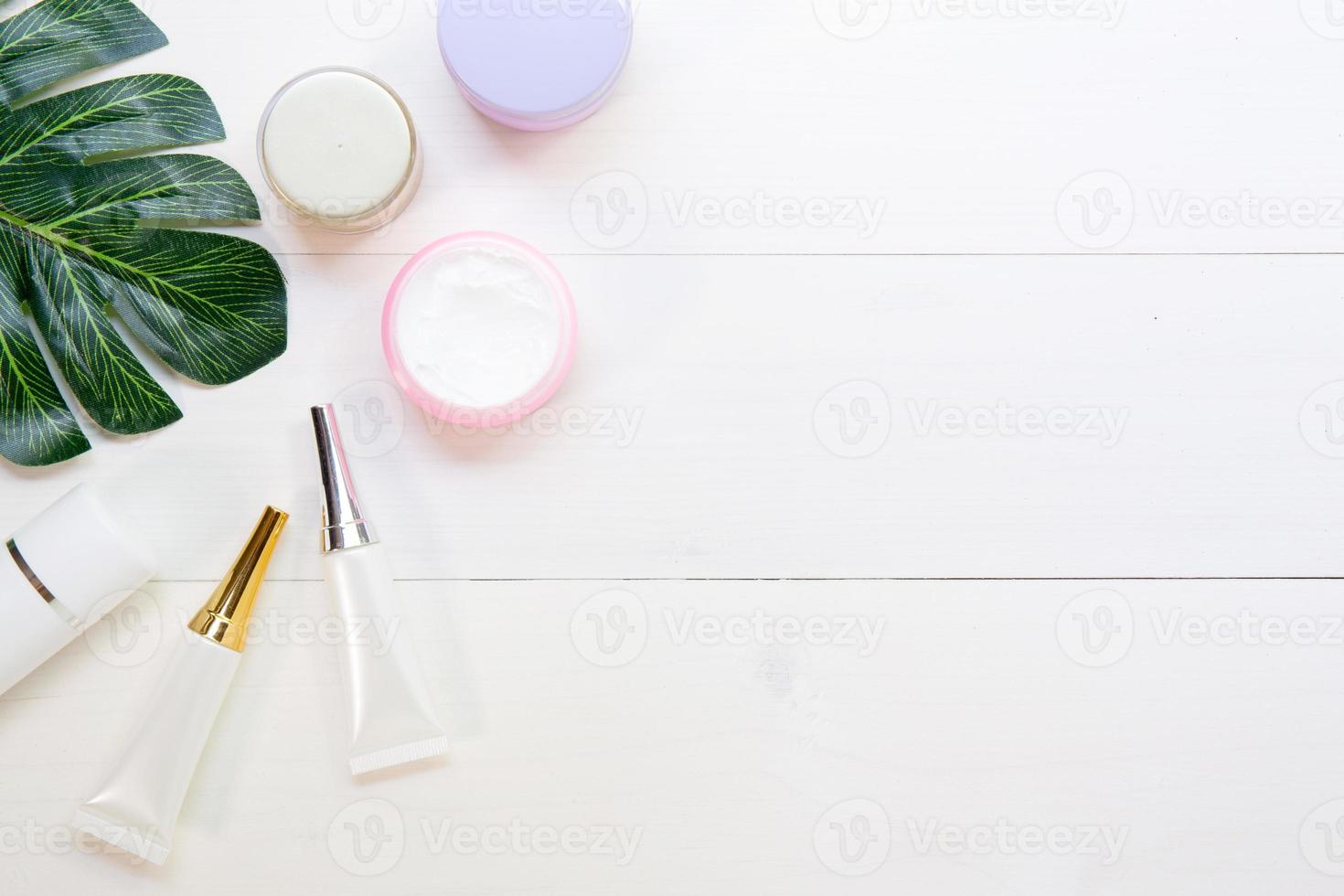 produit cosmétique et de soin de la peau et feuilles vertes sur une table en bois blanc, beauté avec crème de traitement et hydratant sur un bureau en bois, concept de santé et de bien-être, vue de dessus. photo