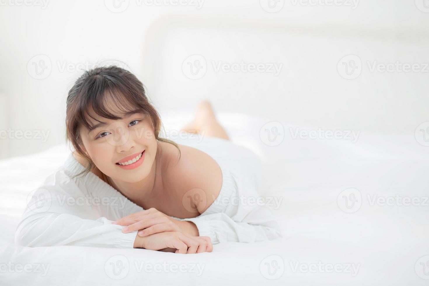 beau portrait jeune femme asiatique allongée et souriante au réveil avec le lever du soleil le matin, beauté jolie fille heureuse et joyeuse reposant sur le lit dans la chambre, mode de vie et concept de détente. photo