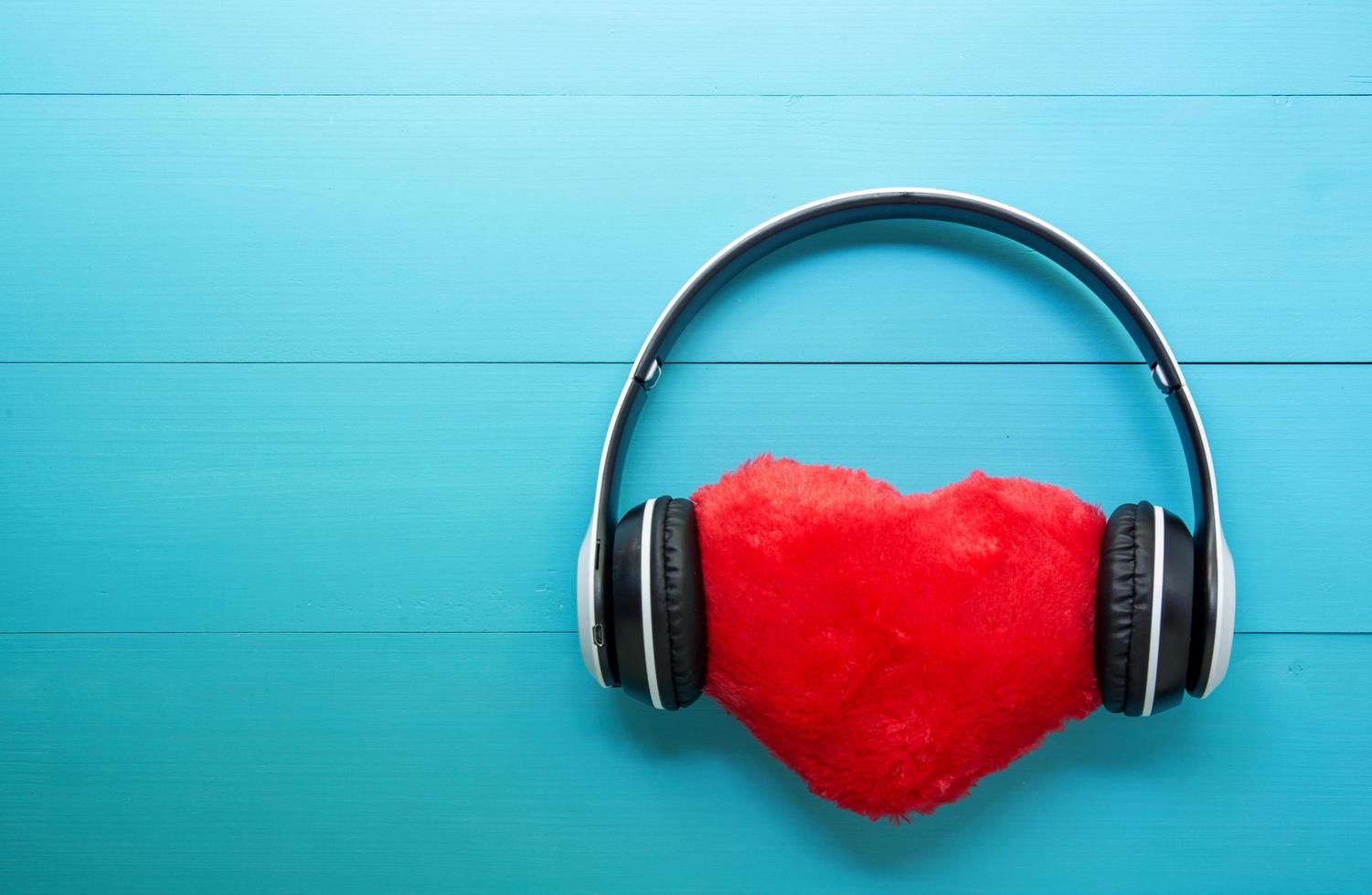 écouteurs et forme de coeur écoutant de la musique sur fond de bois bleu, écouteurs avec radio audio, saint valentin, concept d'amour et de vacances. photo