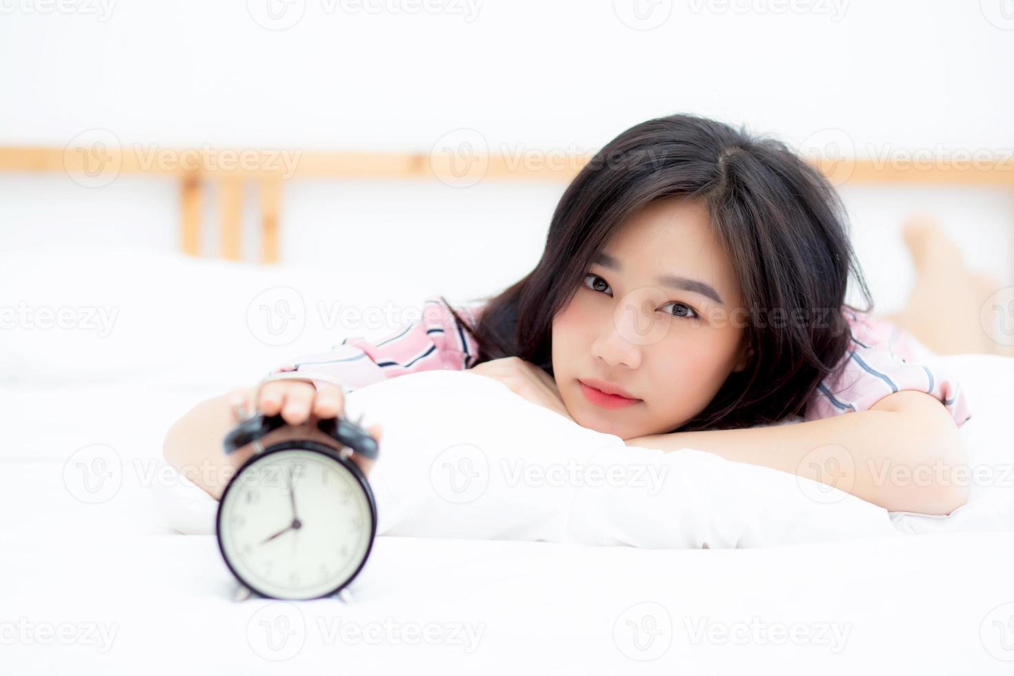 belle jeune femme asiatique éteindre le réveil le matin, se réveiller pour dormir avec réveil, se détendre et concept de style de vie. photo