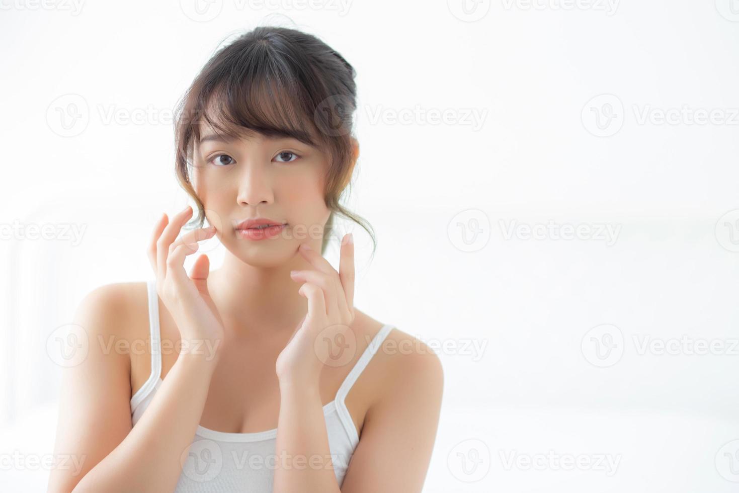 portrait belle femme asiatique maquillage de cosmétique, fille main toucher joue et sourire attrayant, beauté du visage parfaite avec bien-être dans la chambre à la maison avec concept de soins de la peau et de soins de santé. photo