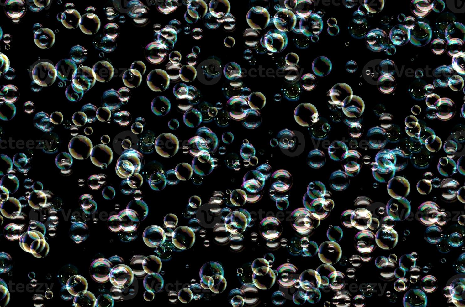 de nombreuses bulles de savon colorées sur fond noir. modèle de texture conceptuelle photo