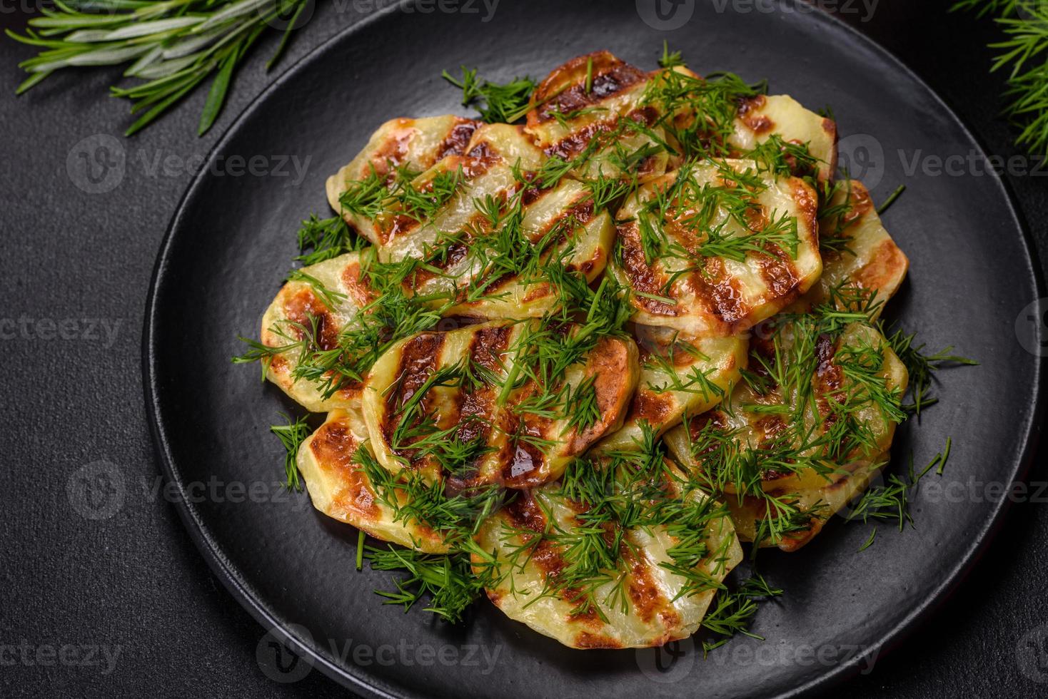 délicieuses tranches de pommes de terre grillées aux épices et herbes sur une plaque noire photo