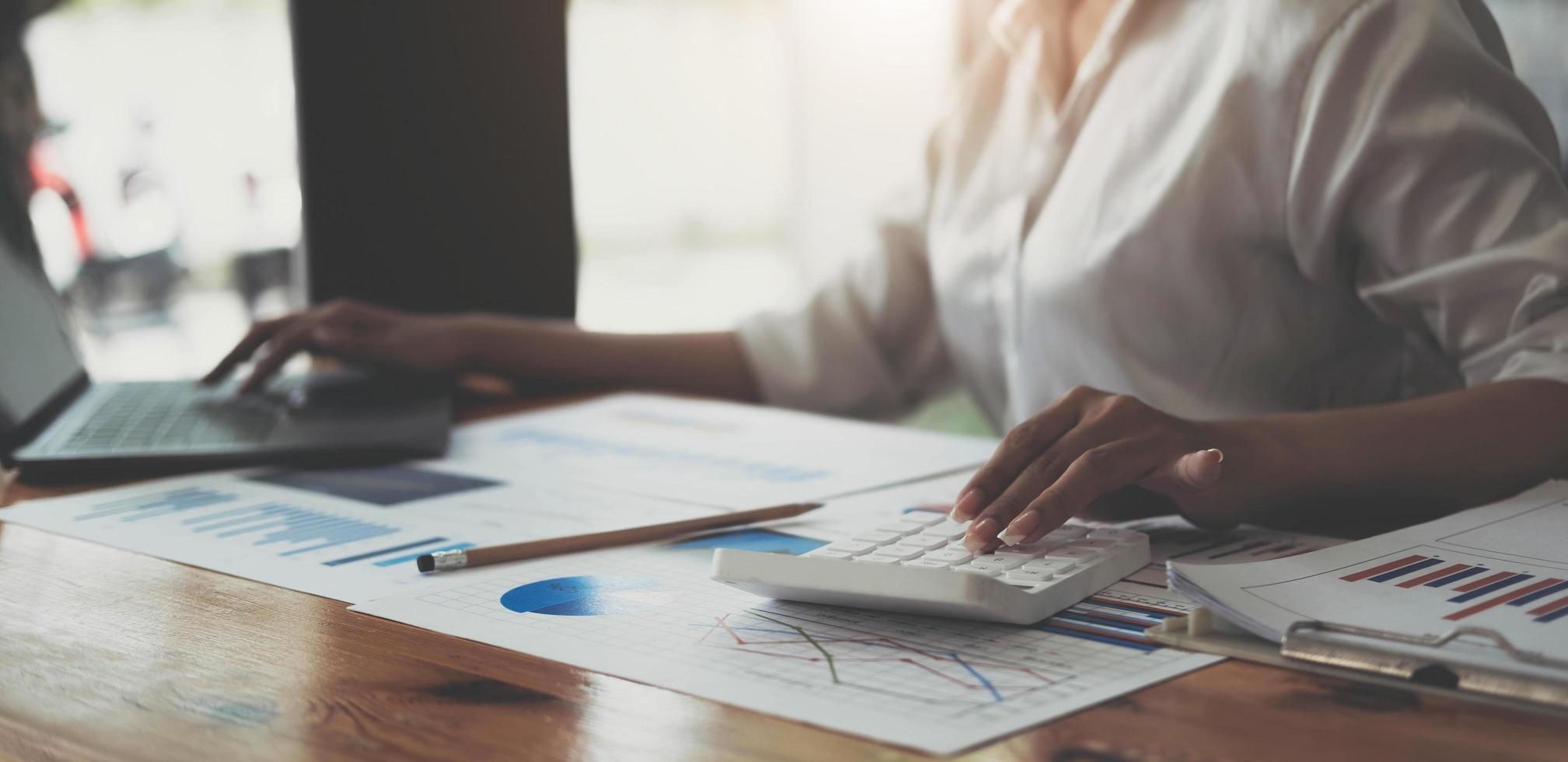 le personnel financier féminin asiatique calcule les résultats de l'investissement pour remettre un rapport à son superviseur lors de la réunion. sur la table au bureau, le concept de calcul des résultats d'investissement photo