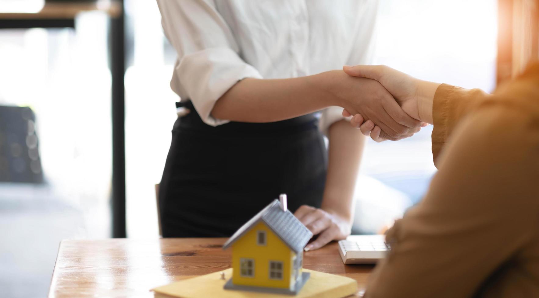 les agents immobiliers et les clients se serrent la main pour féliciter d'avoir signé un contrat pour acheter une maison avec terrain et assurance, poignée de main et bon concept de réponse. photo
