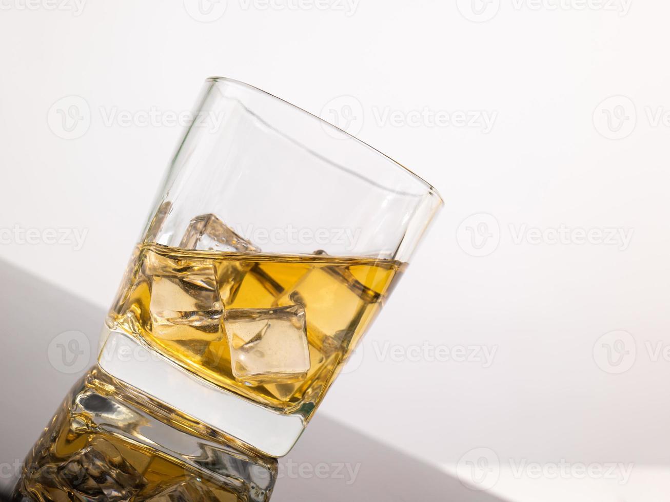 verre à liqueur des éléments translucides en verre sont posés sur une table inclinée. objets vides isolés sur fond blanc photo