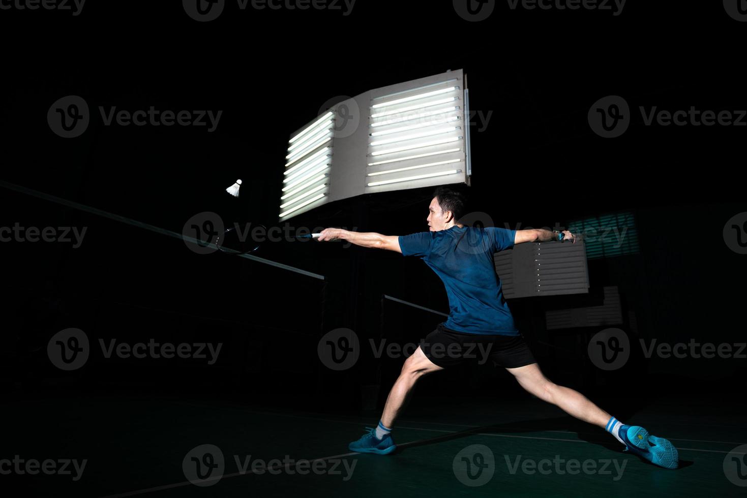 un joueur de badminton professionnel utilise une raquette frappée un coq ou un volant sur le terrain pendant l'échauffement avant la compétition du tournoi en homme seul sur un court intérieur photo