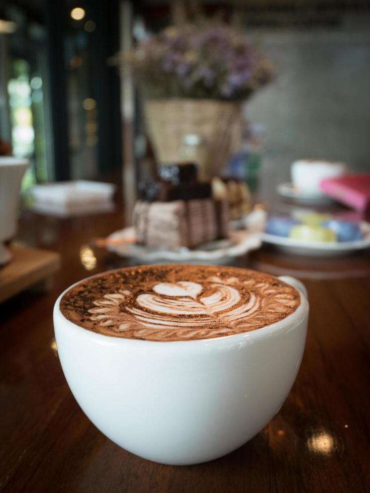 cappuccino avec mousse de lait frais et art latte dans un verre en céramique blanche sur une table en bois dans un café. photo