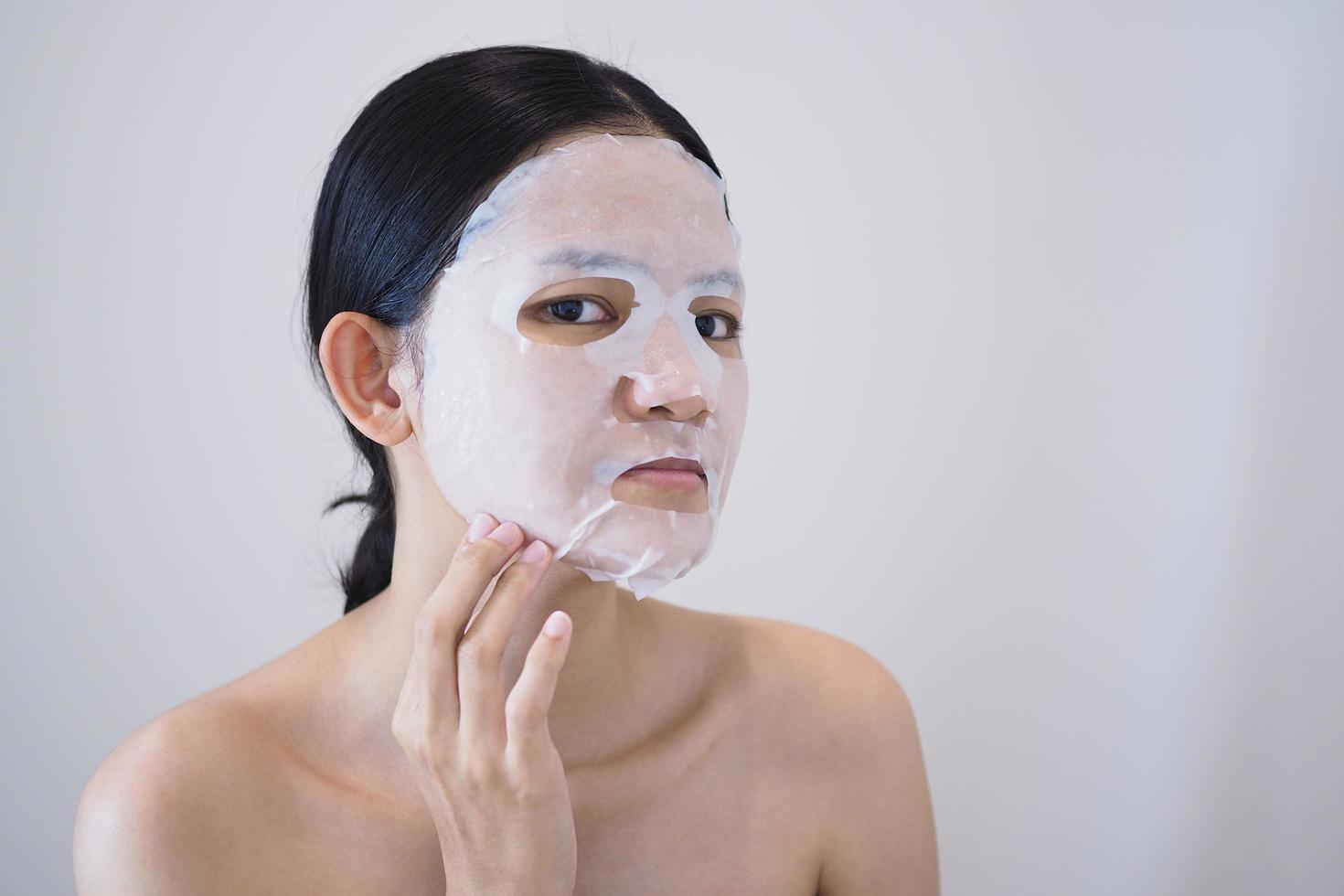 une femme asiatique utilise un masque en feuille sur son visage. photo