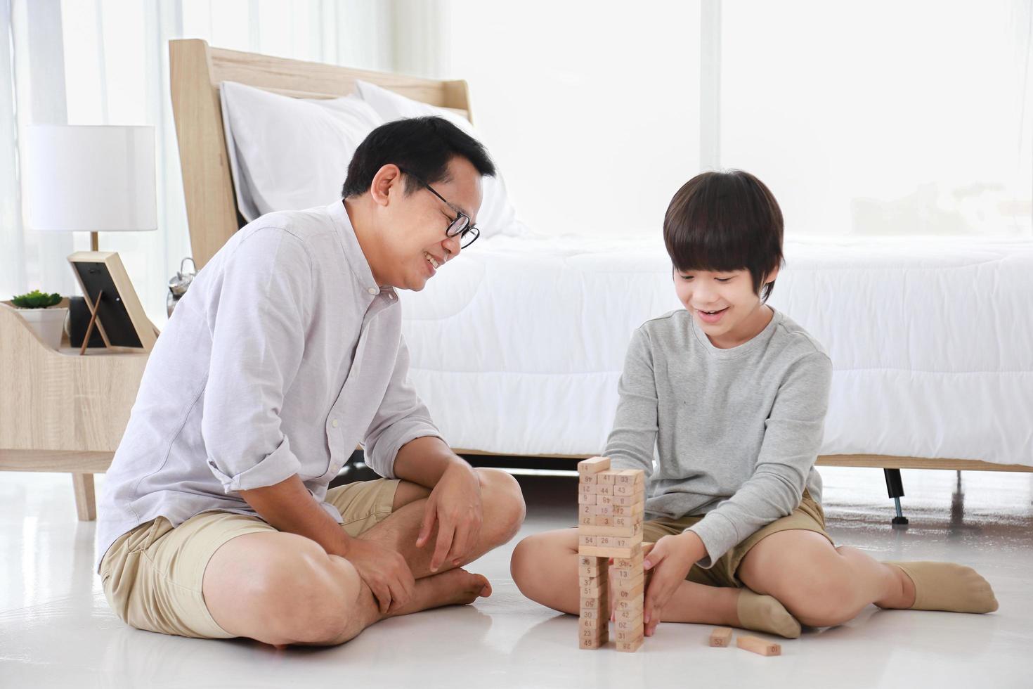 père et fils asiatiques se concentrent sur le jeu de blocs de bois ensemble à la maison pour le concept de divertissement éducatif photo