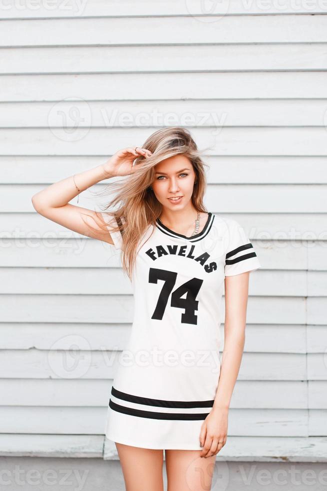 belle fille en t-shirt blanc avec une impression près du mur en bois blanc photo