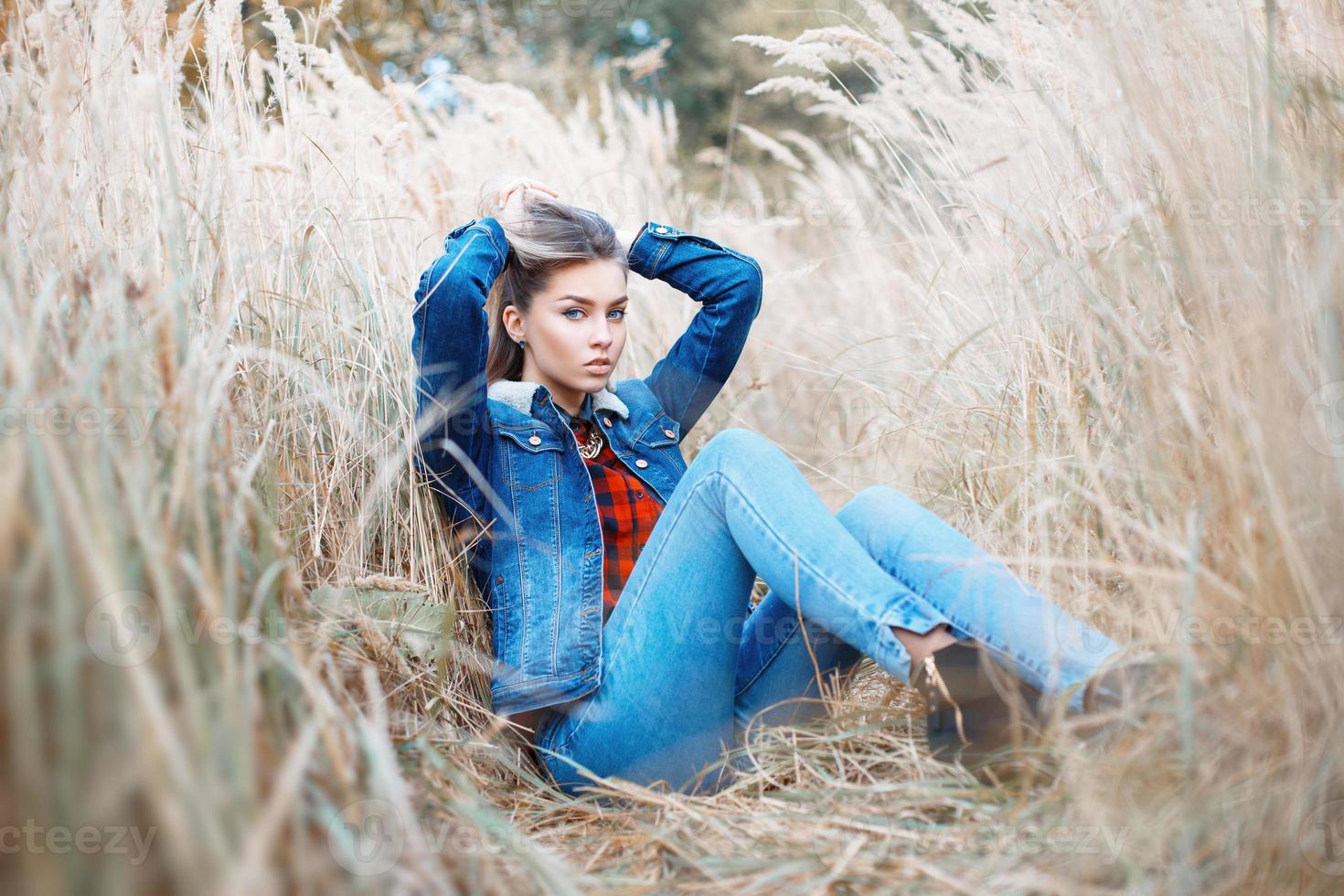 fille à la mode élégante en vêtements jeans dans le champ d'automne. photo