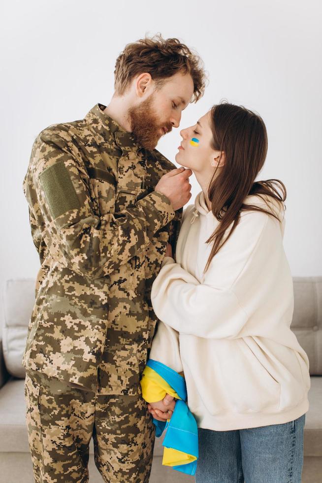 couple ukrainien, homme barbu militaire en uniforme embrasse sa petite amie à la maison photo