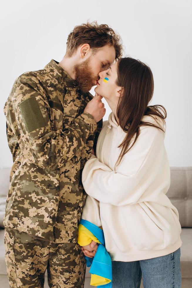 couple ukrainien, homme barbu militaire en uniforme embrasse sa petite amie à la maison photo