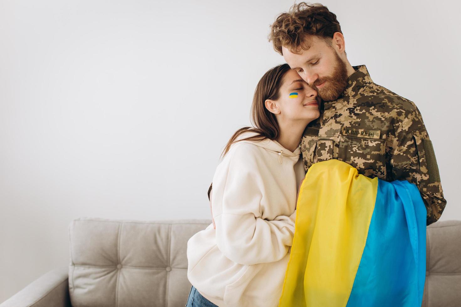 heureux couple ukrainien qui s'est rencontré après la guerre. un militaire barbu en uniforme embrasse sa femme heureuse à la maison. photo