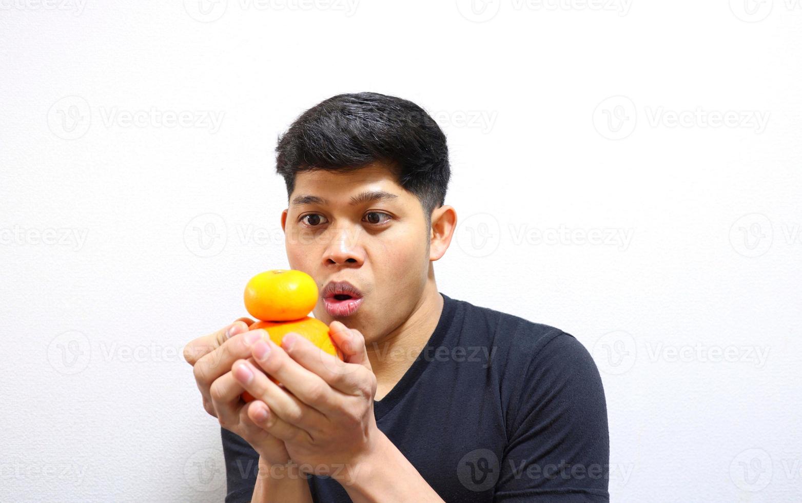 homme asiatique séduisant mangeant des oranges. isolé sur fond blanc photo