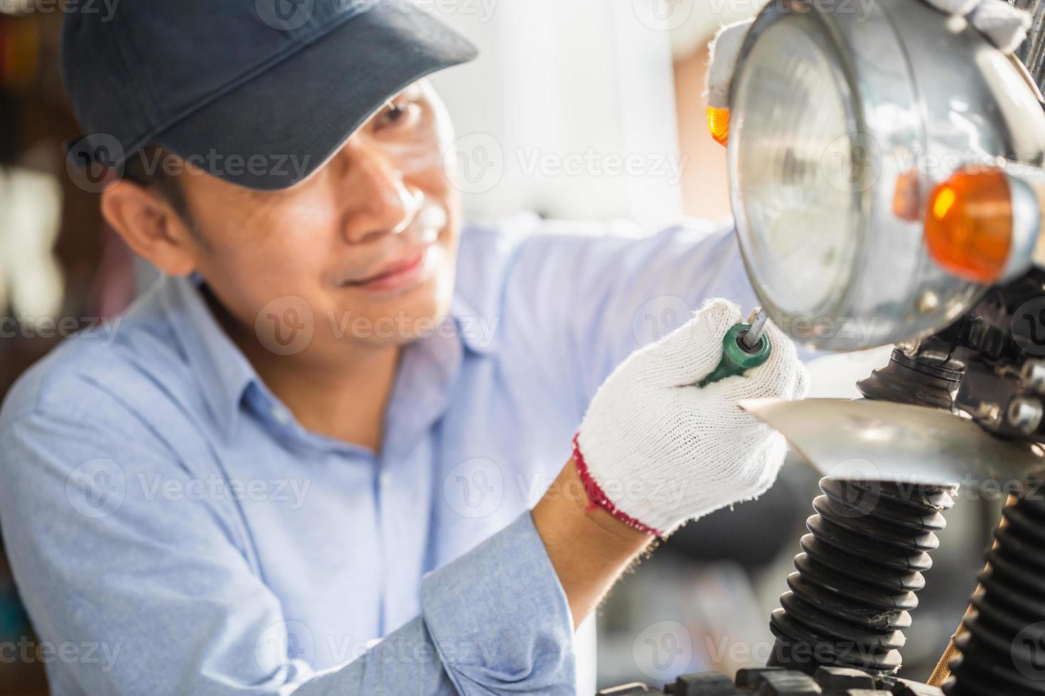 mécanicien réparant la moto dans le garage de l'atelier, homme réparant la moto dans l'atelier de réparation, réparation et entretien photo